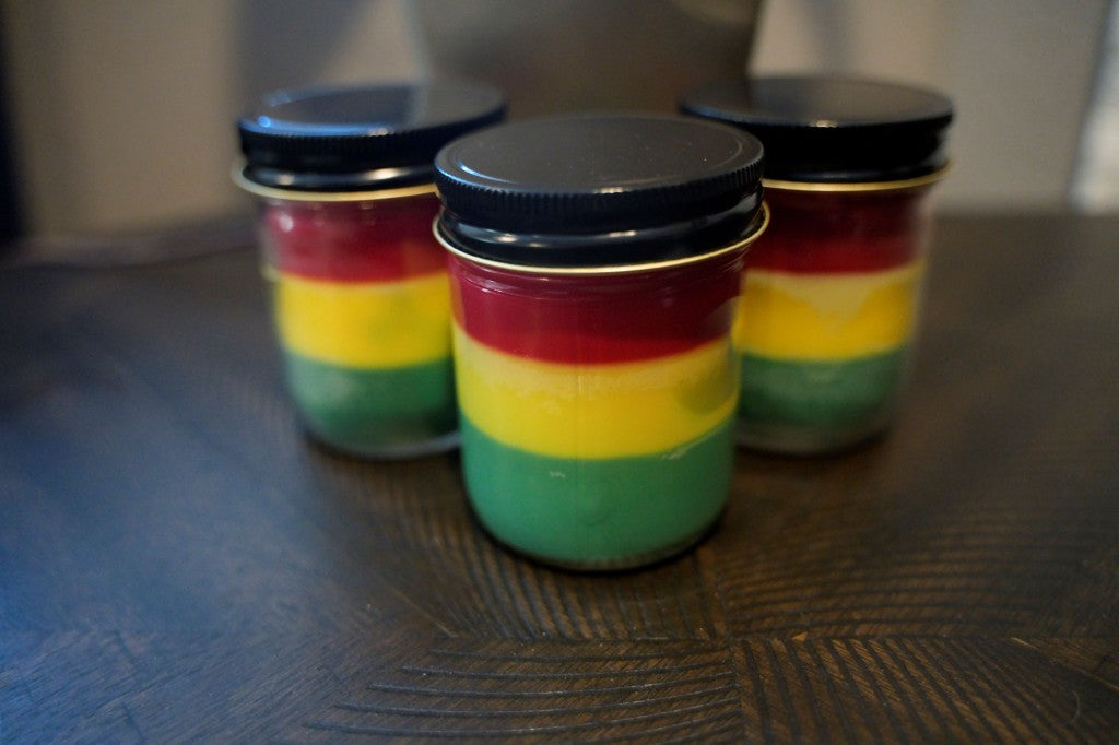 Three jars of layered red, yellow, and green candles