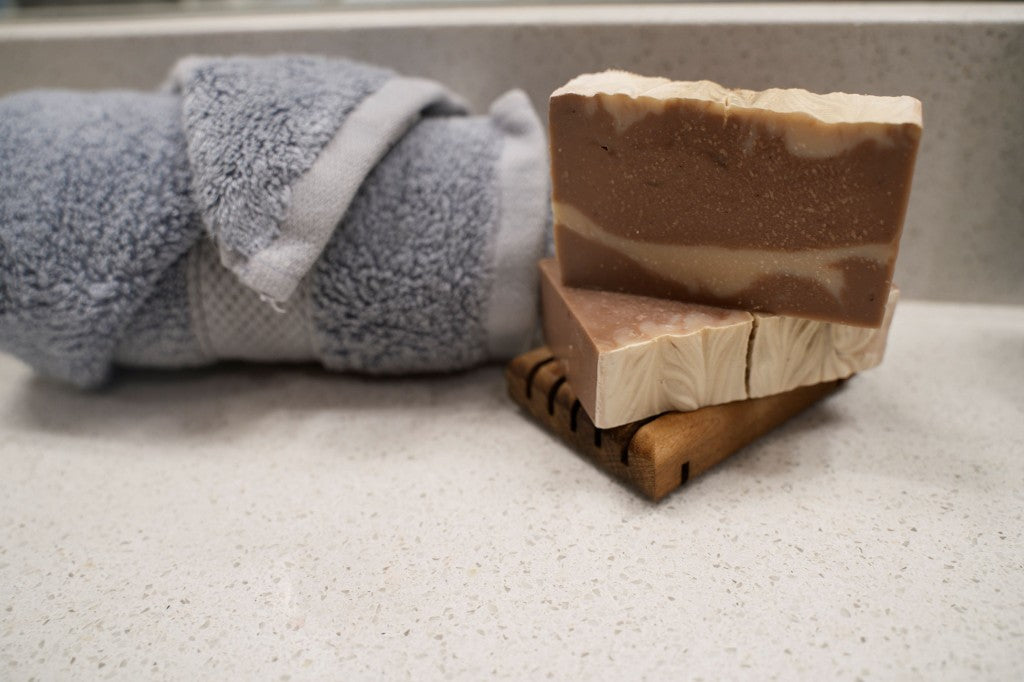 Stacked handmade soap bars beside a rolled blue towel